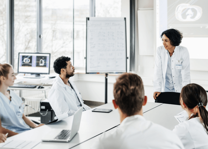 Doctors sit in a board room. 