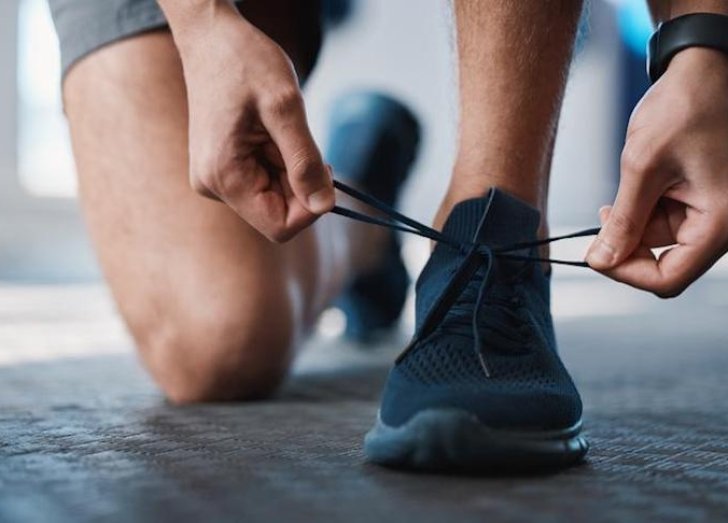 Person bent over tying their sneaker. 