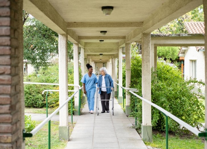 doctor walking outside with patient using a cane.