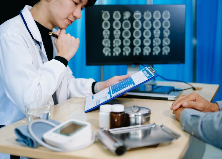 male doctor looking at neurology results on a clipboard.