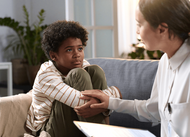 female doctor talking to young boy in a therapy session.