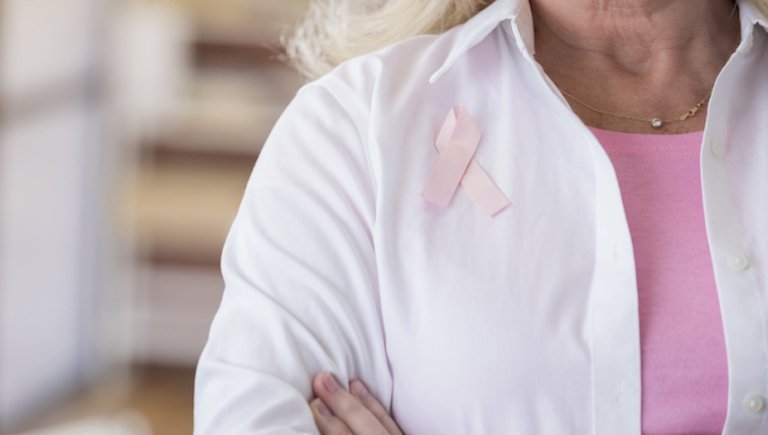 Physician wearing pink breast cancer awareness pin. 