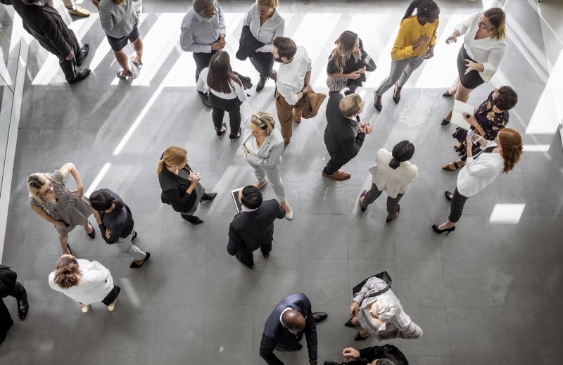 A group of professionals engaged in conversation in an office environment. 